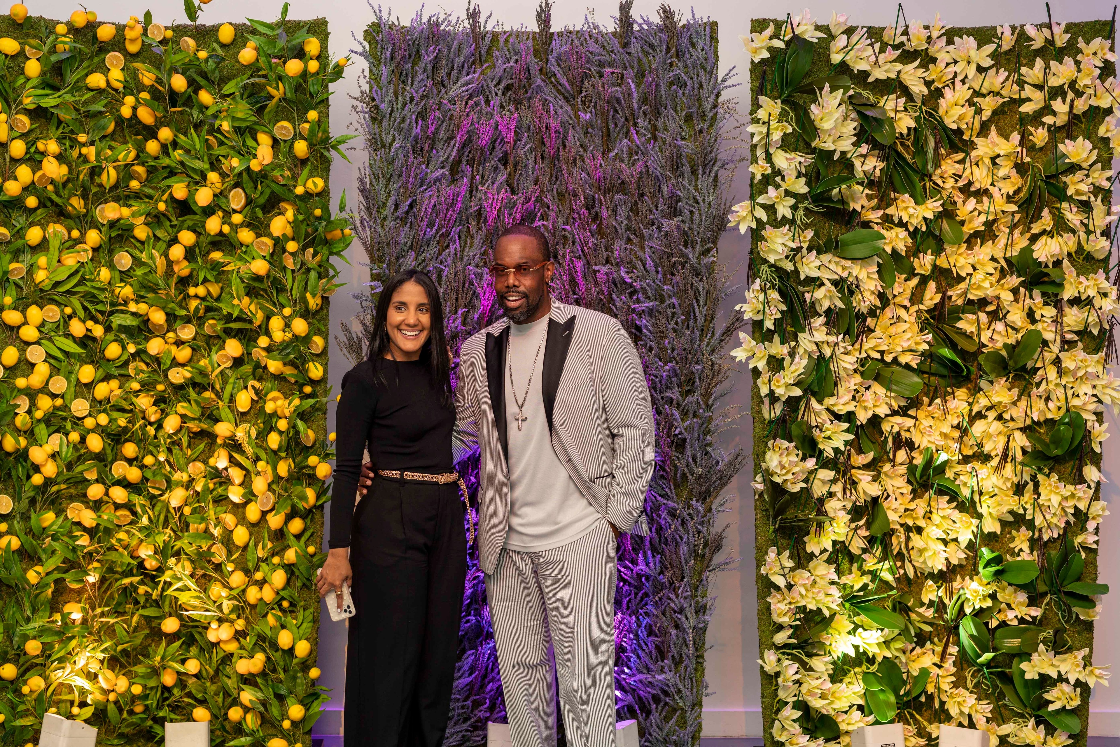 Guests posing in front of a citrus and floral installation