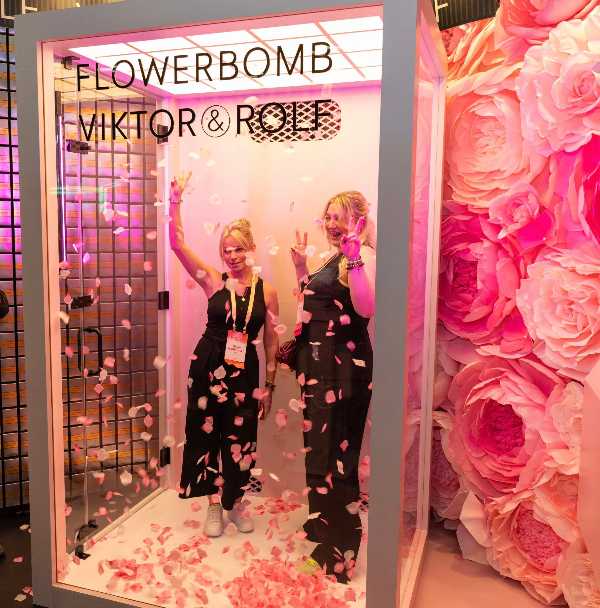Women posing amid falling flower petals at trade show