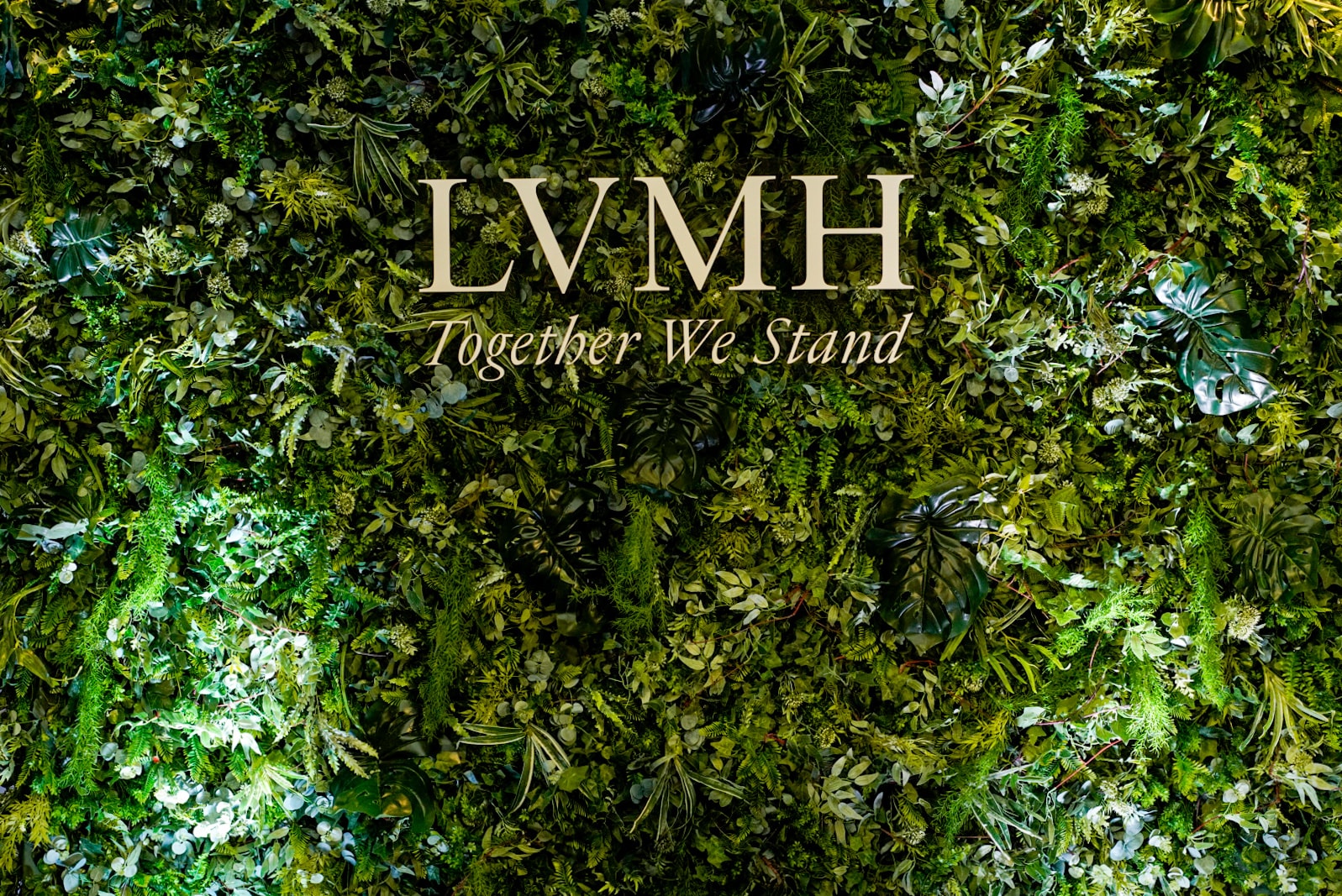 Lush green event wall with Together We Stand message