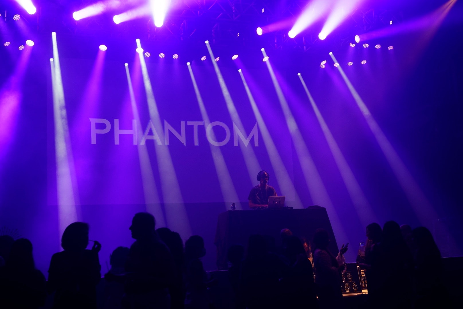 DJ performing under purple stage lights at a live event